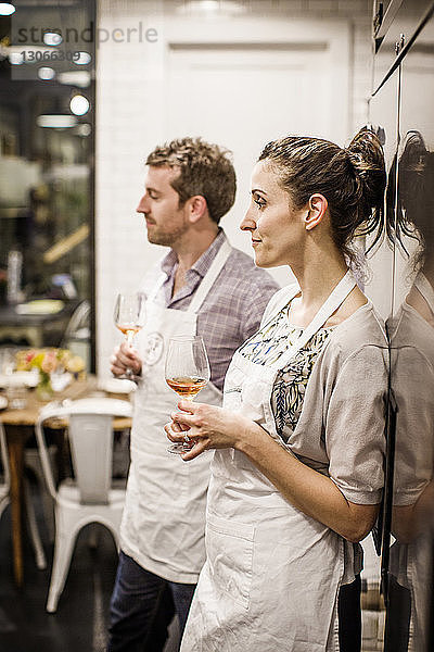Mann und Frau halten Weinbrillen in der Hand  während sie an einer Großküche stehen