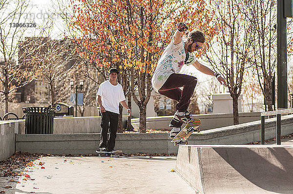 Freunde skateboarden auf der Sportrampe im Park