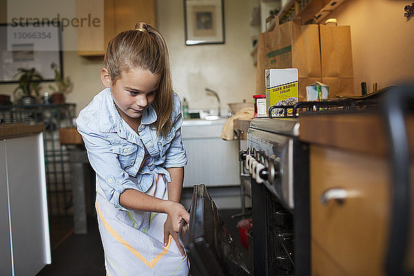 Neugieriges Mädchen betrachtet Muffins  die im Ofen backen