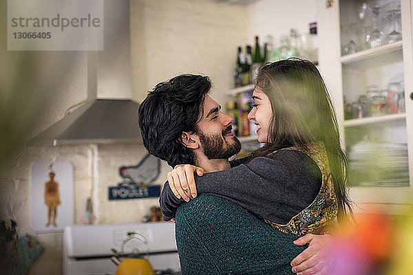 Glückliches Paar umarmt sich im Stehen in der Küche
