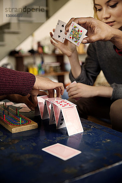 Freunde machen Kartenhaus am Tisch im Wohnzimmer