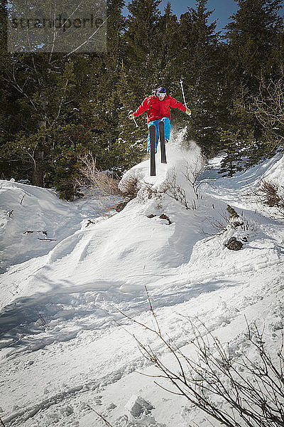 Mann springt beim Skifahren auf schneebedecktem Feld