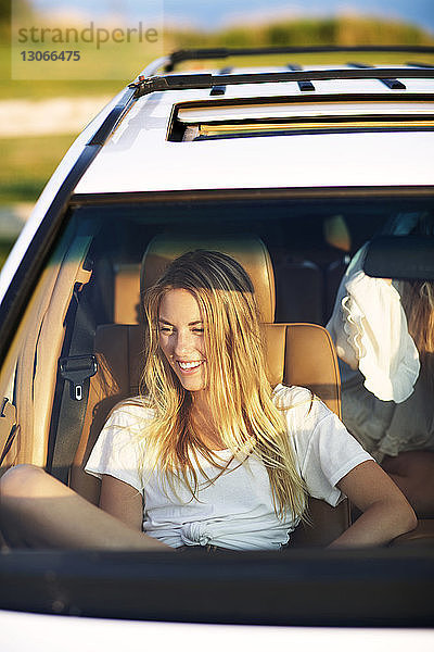 Lächelnde Frau schaut weg  während sie im Auto sitzt