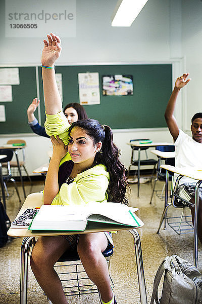 Schüler heben während des Unterrichts im Klassenzimmer die Hand