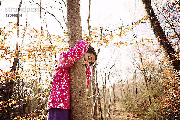Bildnis eines Mädchens  das im Herbst im Hof einen Baumstamm umarmt