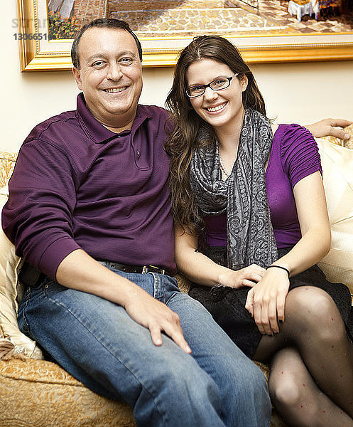 Porträt von Vater und Tochter zu Hause auf dem Sofa sitzend