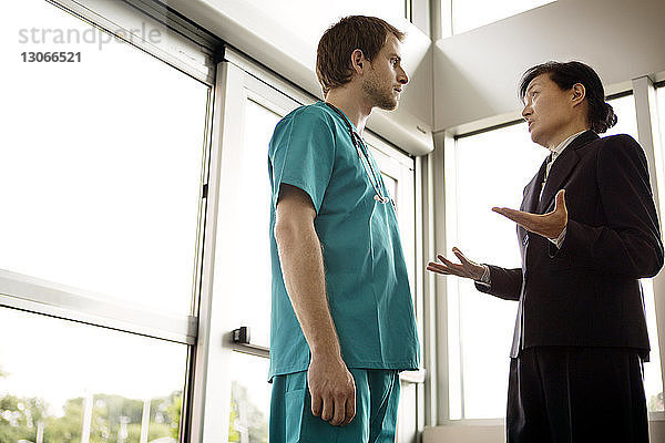 Niedriger Blickwinkel eines Arztes  der mit einer Geschäftsfrau spricht  während er im Krankenhaus steht