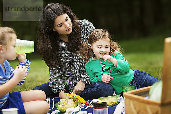 Mädchen lehnt sich beim Sitzen auf dem Feld an die Mutter