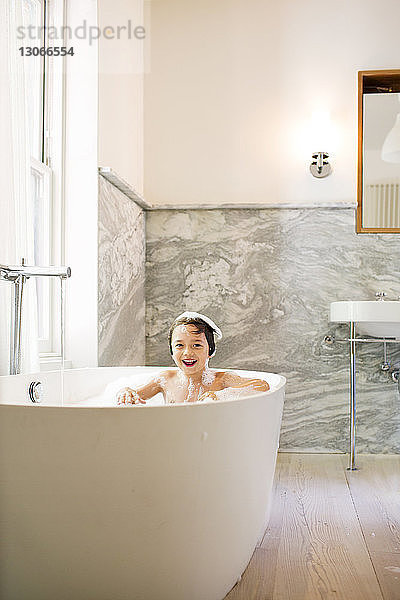 Porträt eines lächelnden Jungen beim Baden in der Badewanne