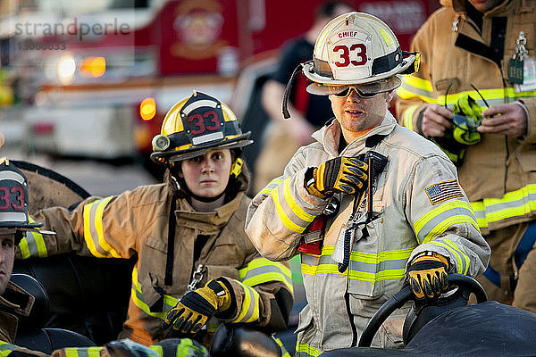 Feuerwehrmann hält Walkie-Talkie in der Hand  während er seinen Kollegen zur Seite steht