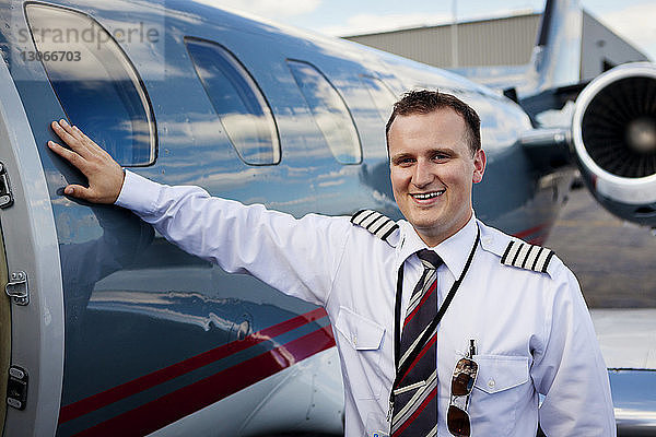 Porträt eines glücklichen Piloten  der am Flugzeug steht