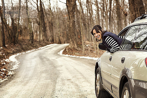 Porträt einer glücklichen Frau  die aus dem Auto schaut