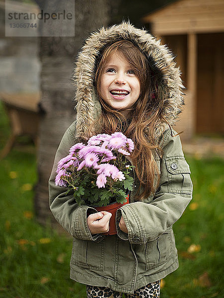 Mädchen trägt Topfpflanze  während sie im Hinterhof steht