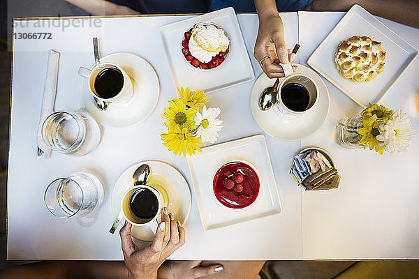 Ausgeschnittenes Bild von Freunden bei Kaffee und Dessert am Tisch im Restaurant