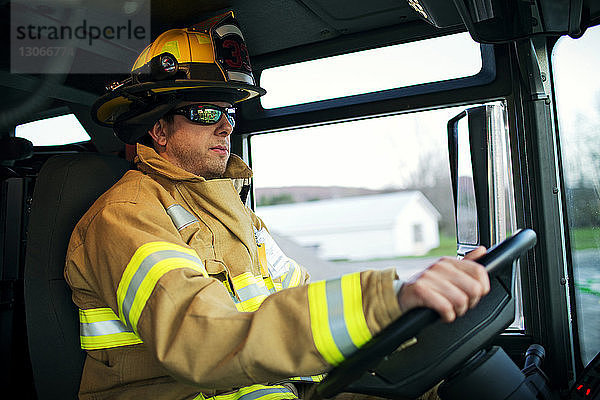 Zuversichtlicher Feuerwehrmann fährt Feuerwehrfahrzeug