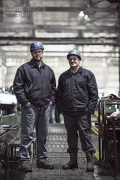 Porträt von Arbeitern mit Händen in der Tasche stehend in der Fabrik