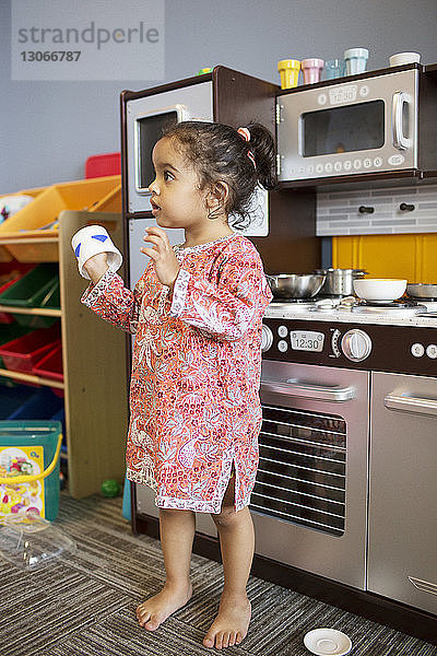 Mädchen hält Tasse  während sie zu Hause in der Küche steht