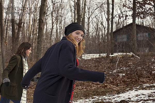 Porträt einer Frau  die im Winter mit einem Freund im Wald spazieren geht