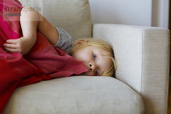 Porträt eines zu Hause auf dem Sofa liegenden Mädchens