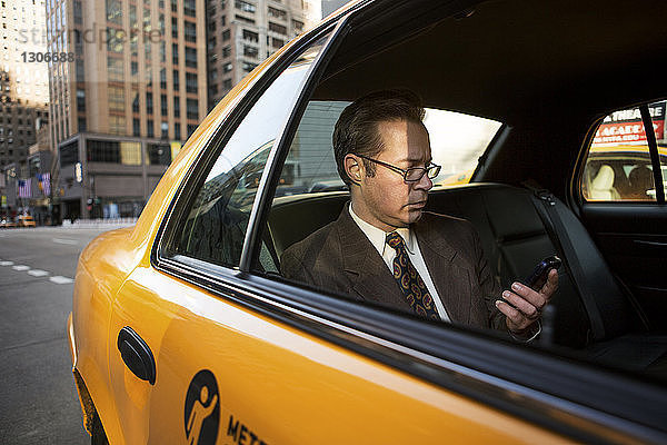 Geschäftsmann mit Mobiltelefon im Taxi