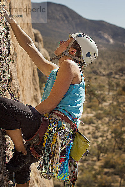 Niedrigwinkelansicht einer Frau  die am Fels gegen den Berg klettert