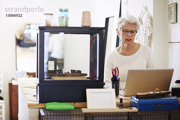 Ältere Frau benutzt Laptop-Computer in einer Boutique
