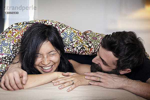 Glückliches Paar unterhält sich zu Hause im Bett liegend
