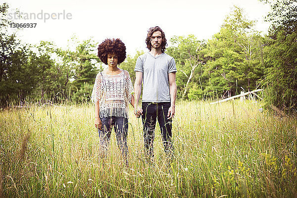 Porträt eines selbstbewussten Paares auf Grasfeld stehend