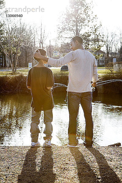 Rückansicht von Vater und Sohn beim Angeln im See