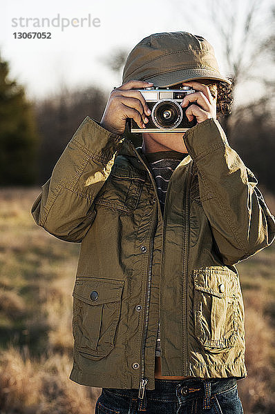 Junge beim Fotografieren im Stehen auf dem Feld