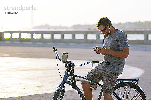 Mann benutzt Smartphone  während er auf dem Fahrrad sitzt