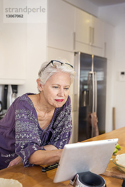 Frau benutzt Tablet-Computer  während sie in der Küche steht