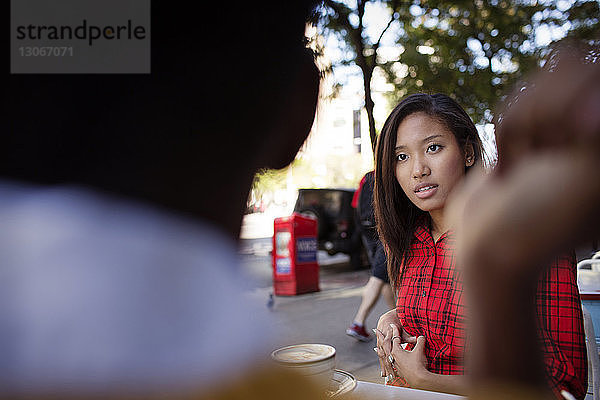 Frau sieht Freundin an  während sie im Straßencafé sitzt