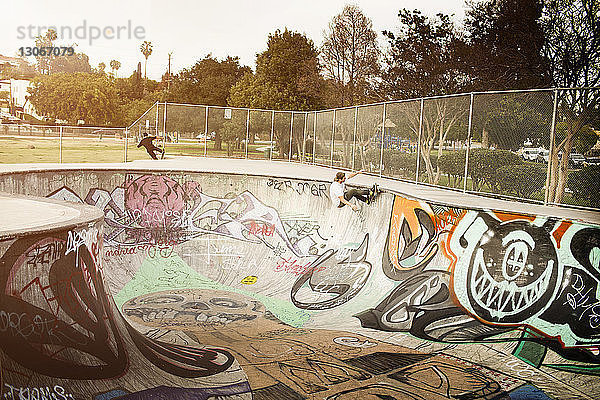 Mann fährt Skateboard auf der Sportrampe im Park