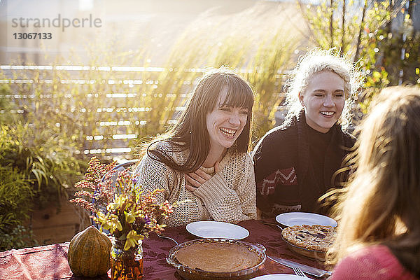 Fröhliche Freundinnen sitzen während der Gartenparty am Tisch im Freien