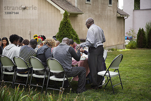 Familie betet am Frühstückstisch auf dem Rasen