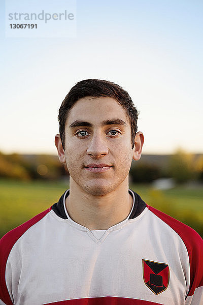 Porträt eines selbstbewussten Rugby-Spielers auf dem Spielfeld vor klarem Himmel
