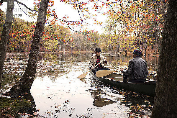 Freunde rudern Boot auf dem See inmitten von Bäumen im Wald
