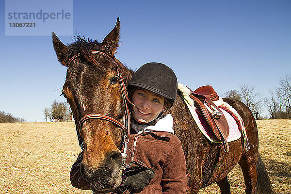 Bildnis eines glücklichen Jungen mit Pferd auf einem Feld vor klarem Himmel stehend