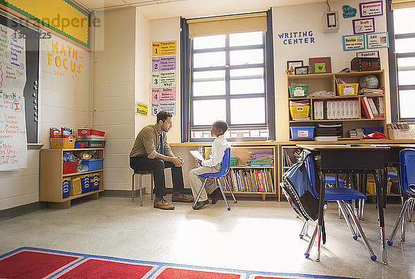 Lehrer hört dem Jungen zu  während er während der Prüfung im Klassenzimmer sitzt