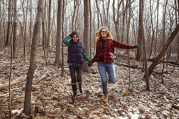 Freunde halten beim Laufen im Wald Händchen
