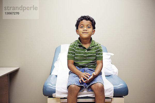 Porträt eines Jungen  der im Krankenhaus auf einem Bett sitzt