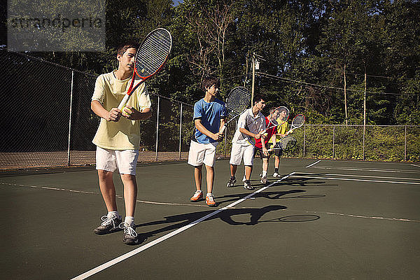 In der Reihe stehende Spieler spielen Tennis auf dem Platz