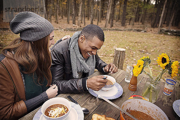 Glückliches Paar beim Essen am Tisch im Wald