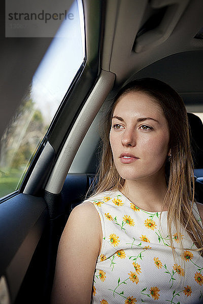 Nachdenkliche Frau schaut weg  während sie im Auto sitzt