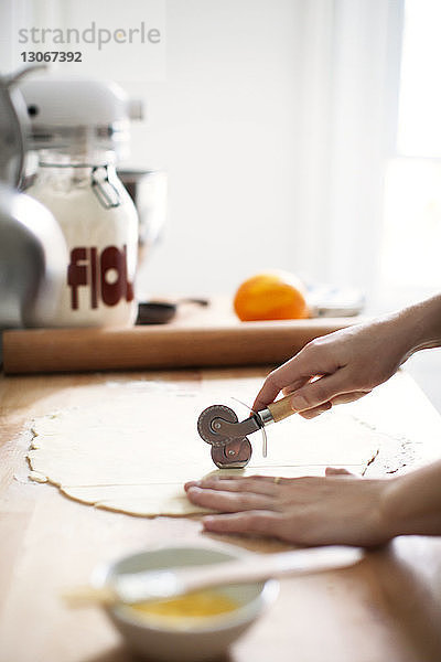 Ausgeschnittenes Bild einer Frau  die zur Zubereitung von Kuchen Teig durch den Ausstecher schneidet