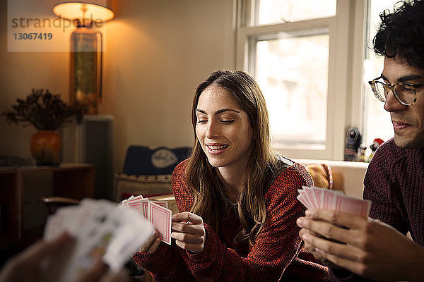 Glückliche Freunde spielen Karten  während sie sich zu Hause ausruhen