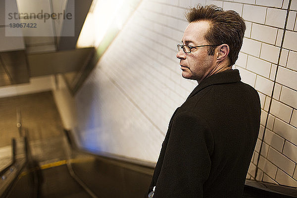 Rückansicht eines auf der Rolltreppe stehenden Geschäftsmannes