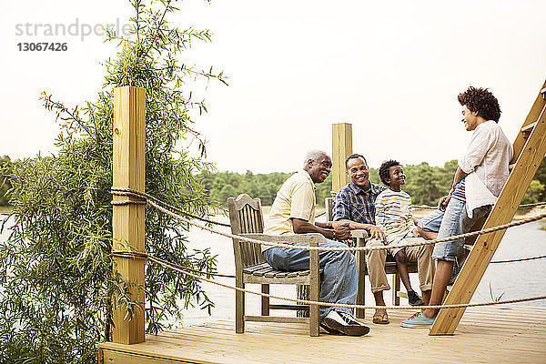 Mehrgenerationen-Familie spricht am Pier am See gegen den klaren Himmel