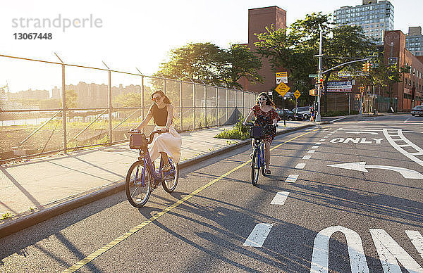 Glückliche Freundinnen fahren Fahrrad auf der Straße in der Stadt